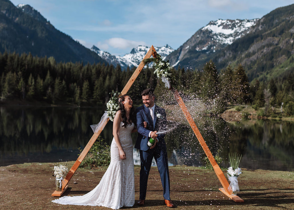 Married couple popping champagne after their intimate wedding at Gold Creek Pond