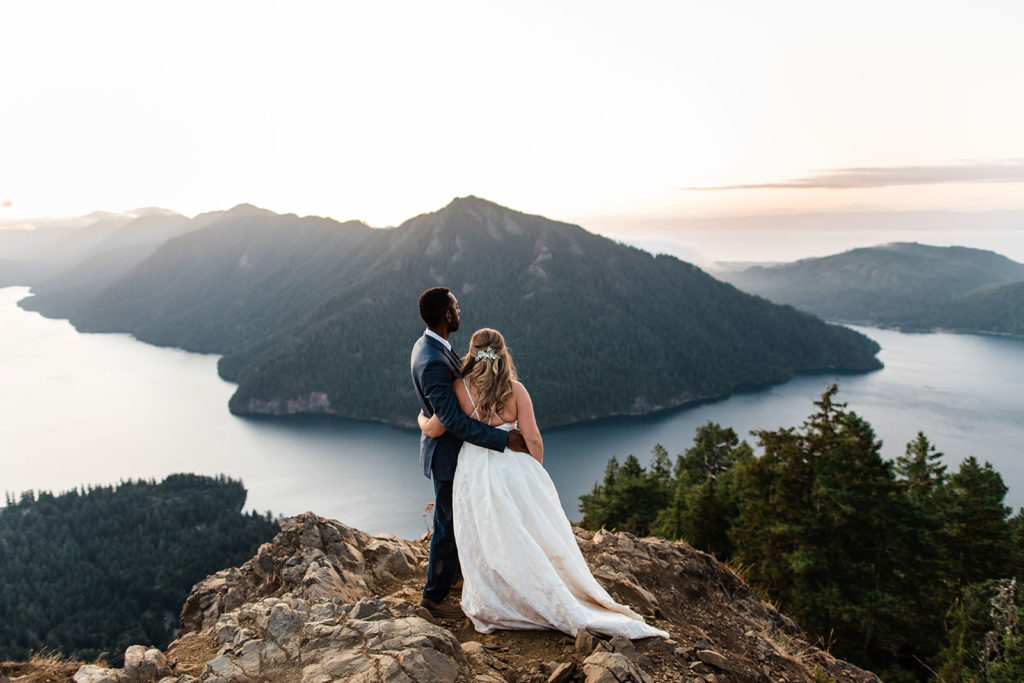 Bride and groom holding each other while lookout out at Lake Crescent