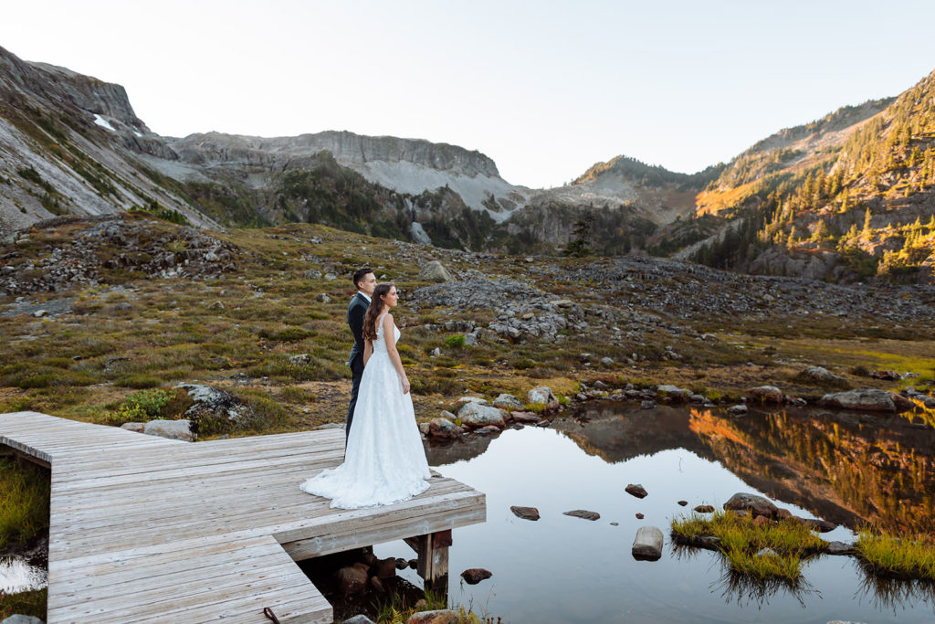 Bride and groom standing on a dock with their dogs at Bagley Lakes during their elopement