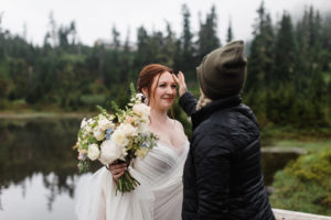 Professional hair and makeup artist fixing a bride's hair just before her elopement ceremony at Picture Lake in Mt Baker