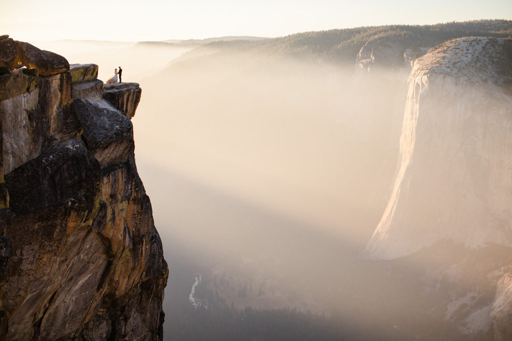 Bride and groom standing on the ledge of a cliff at Taft Point in Yosemite National Park for their adventure elopement with Stephanie Keegan Photography