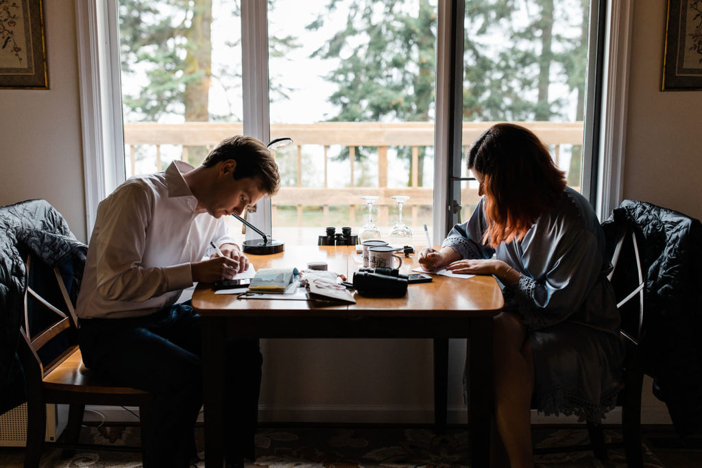 Bride and groom writing their wedding vows to each other in a cabin